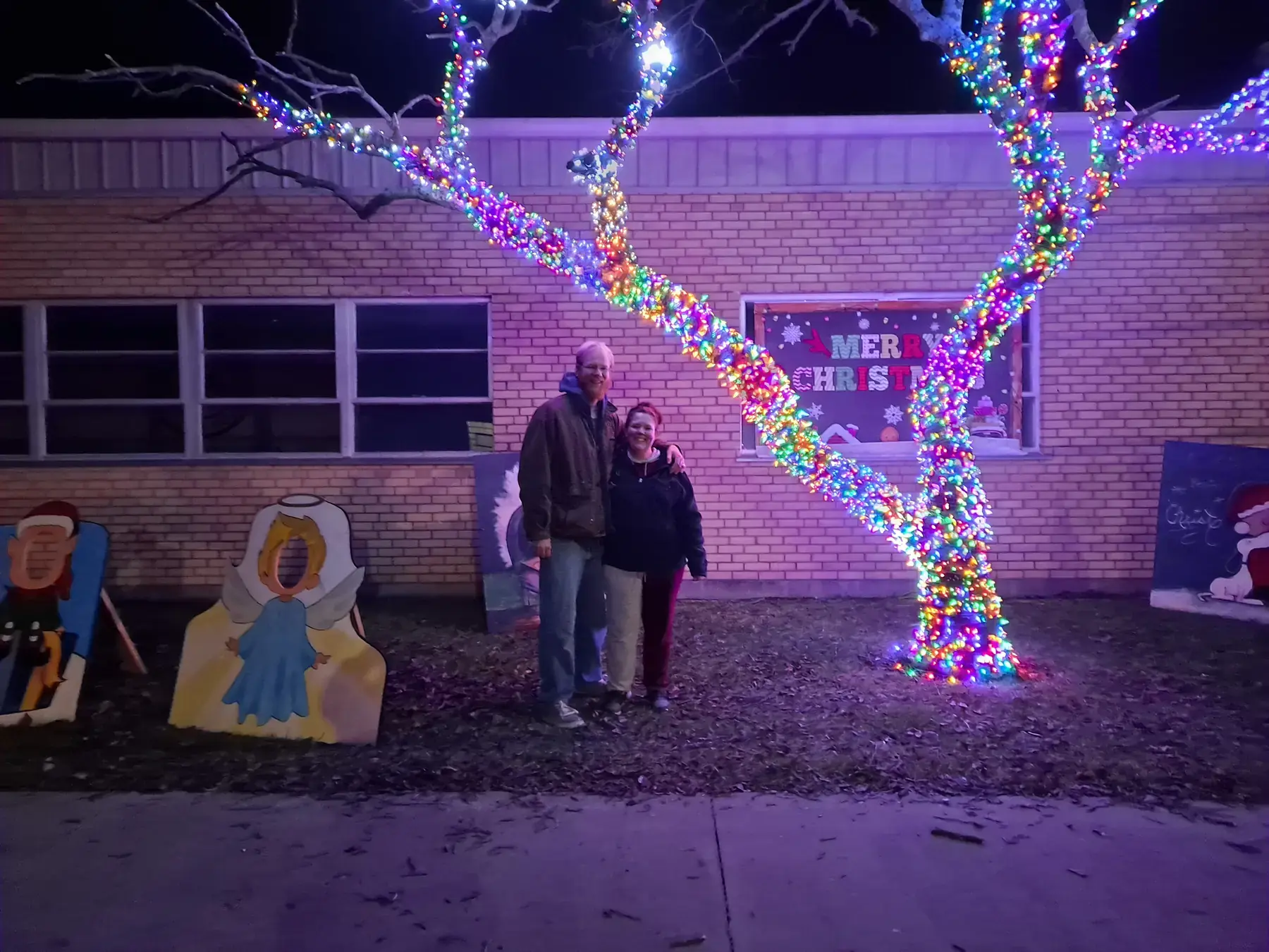 Trees wrapped in colorful Christmas lights at a small-town light display