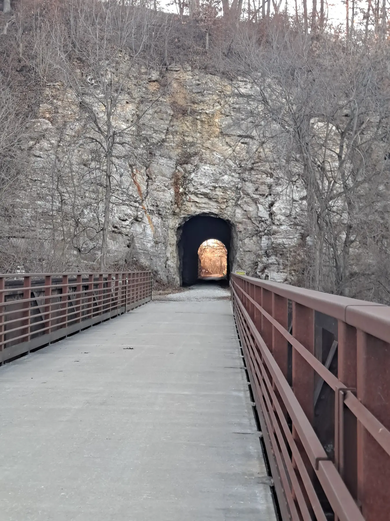 Walking trail bridge leading to a tunnel cut through solid rock