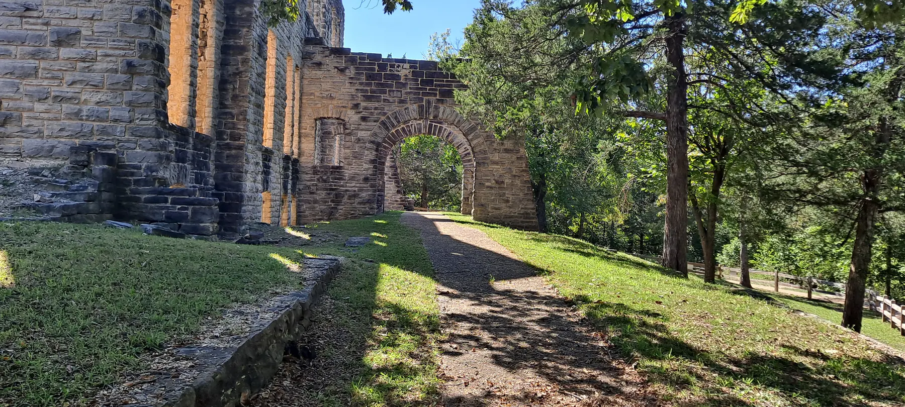 Stone castle ruins with an arched walkway on a sunny hillside