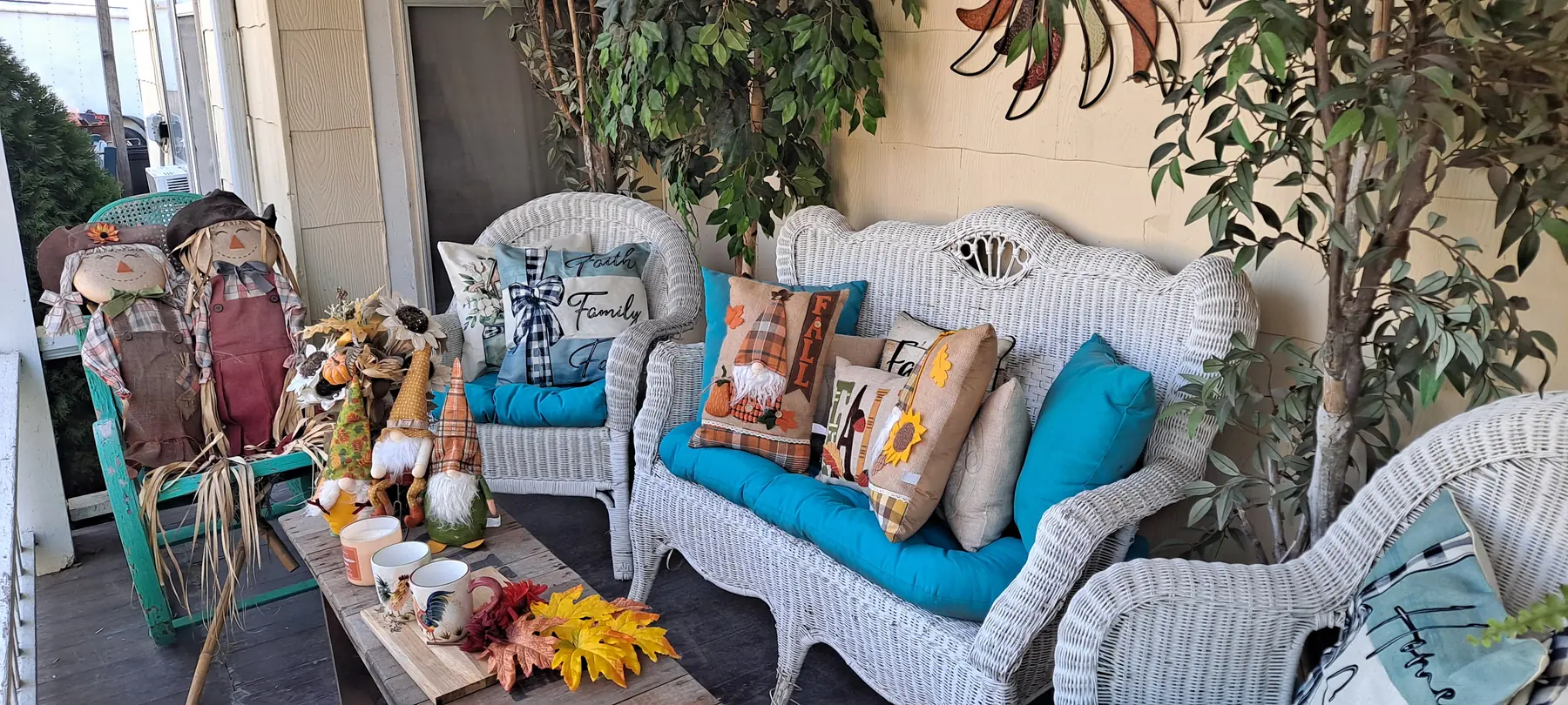 Front porch decorated for fall with scarecrows, gnomes, and pillows
