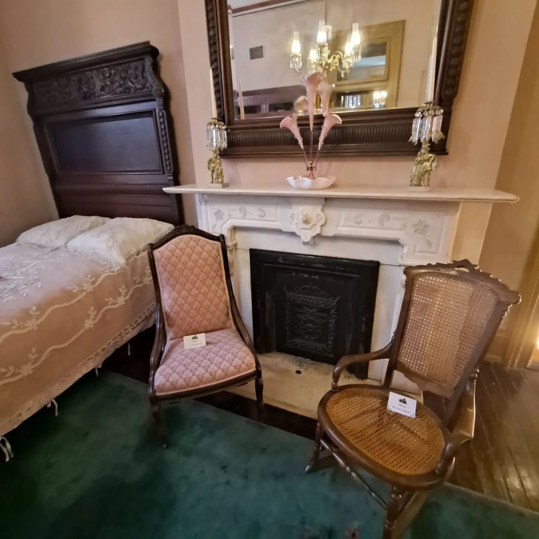 Victorian parlor with marble fireplace, mirror, and antique chairs