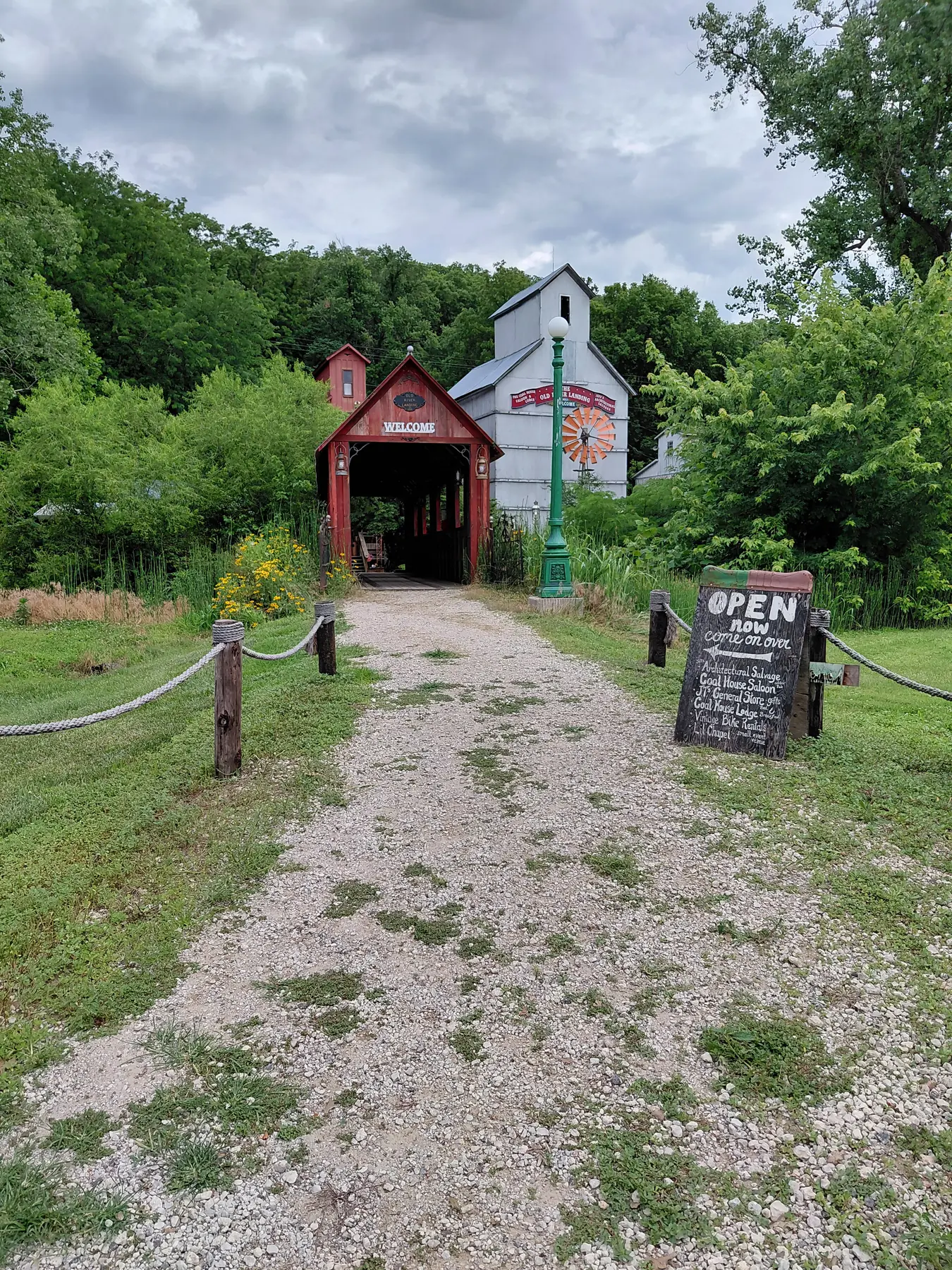 Red covered-bridge style welcome entrance beside an old white landing building