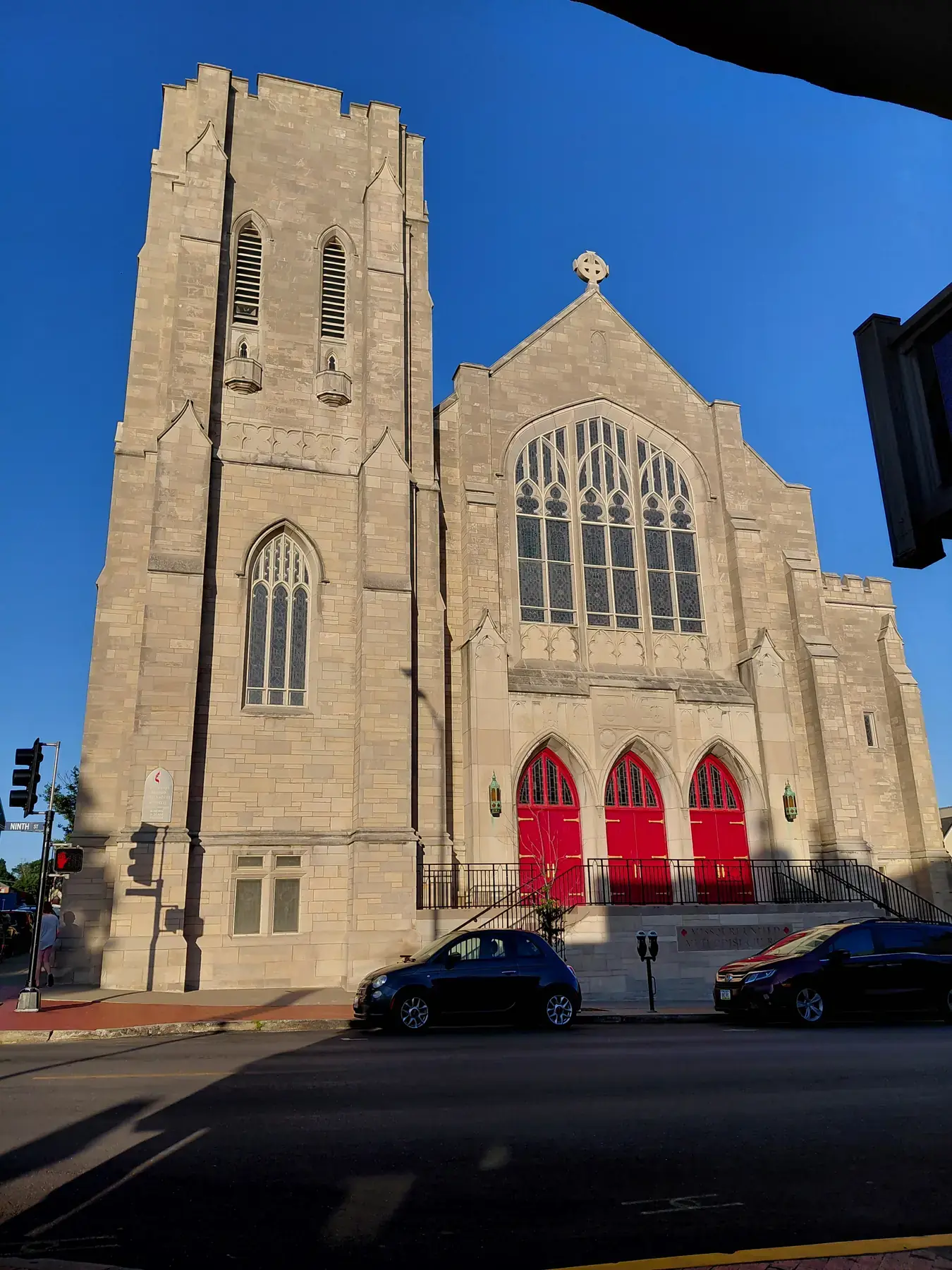 Gothic stone church with bright red doors in evening light